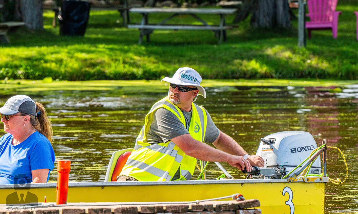 Boat operator navigates along wooden dock during summer day on the lake.