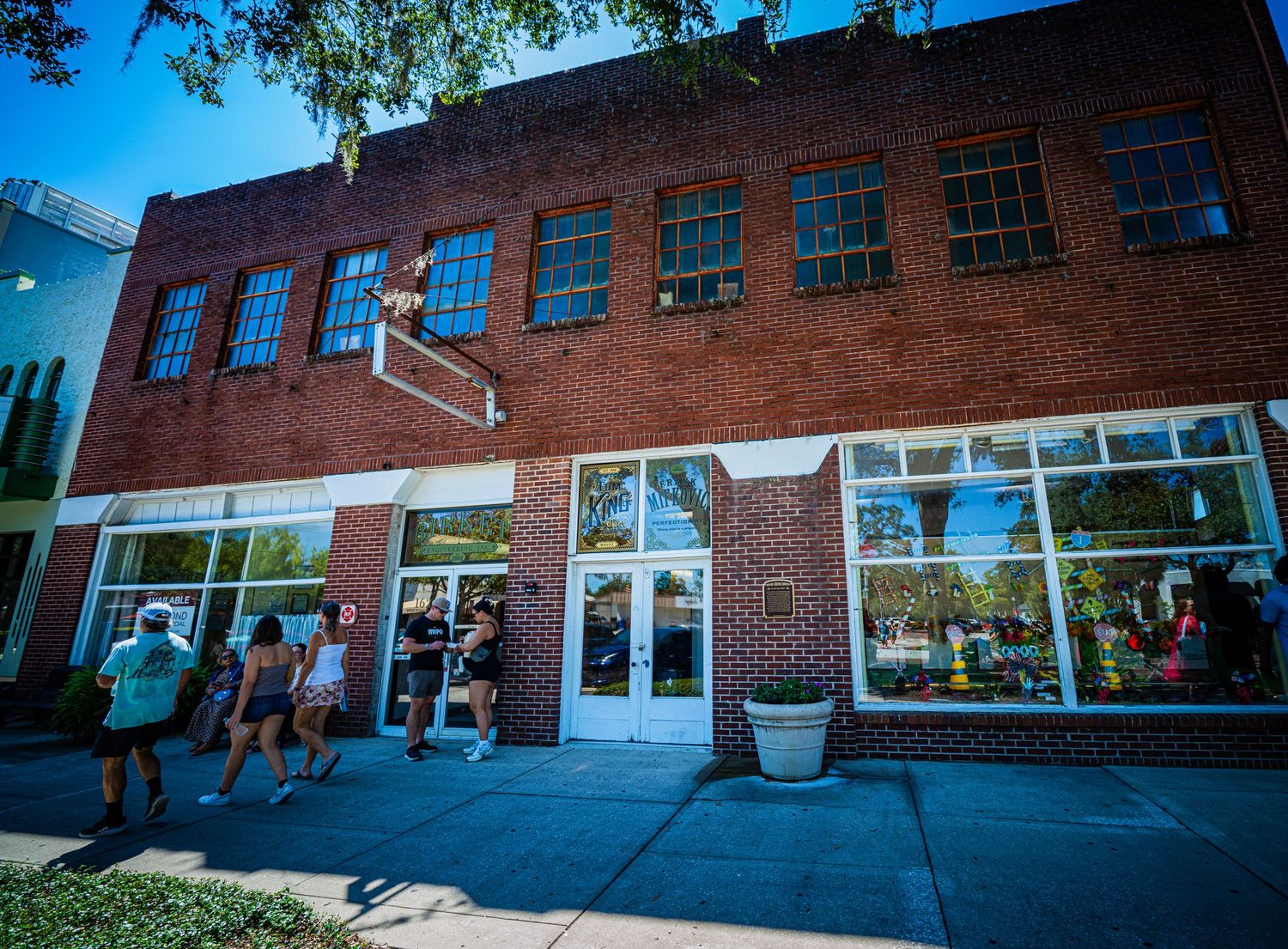 Panoramic view of a brick commercial building exterior with large windows and walkway.