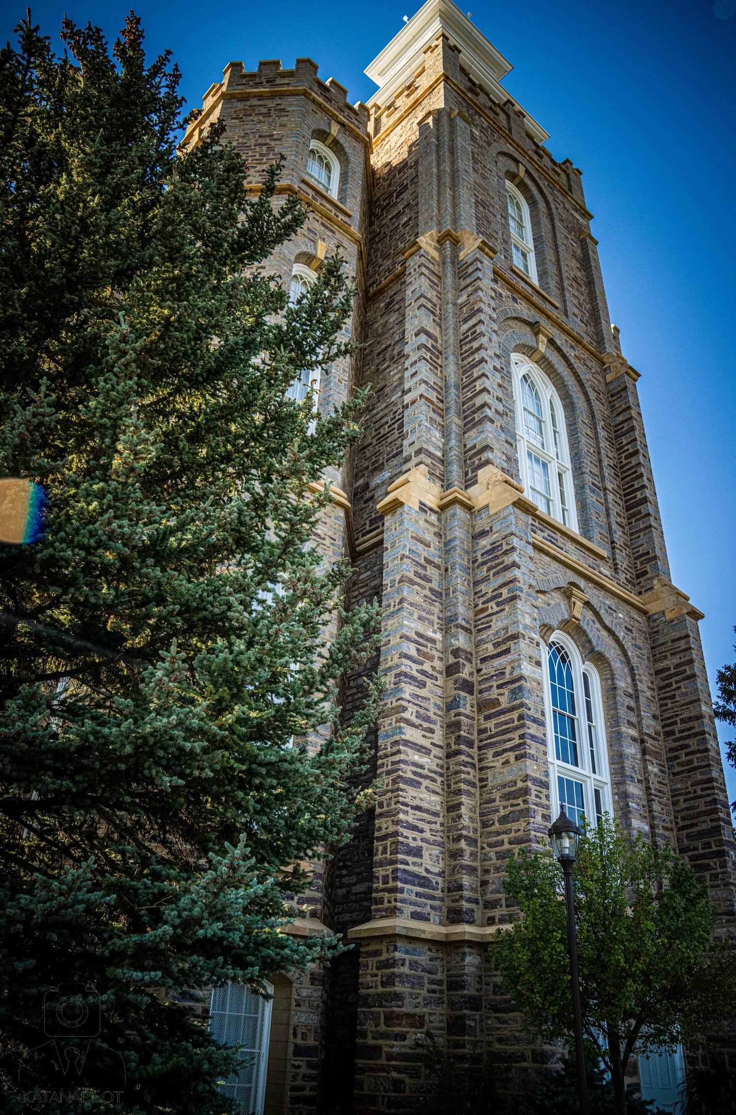 Towering stone architecture with gothic windows and ornate details viewed from below.