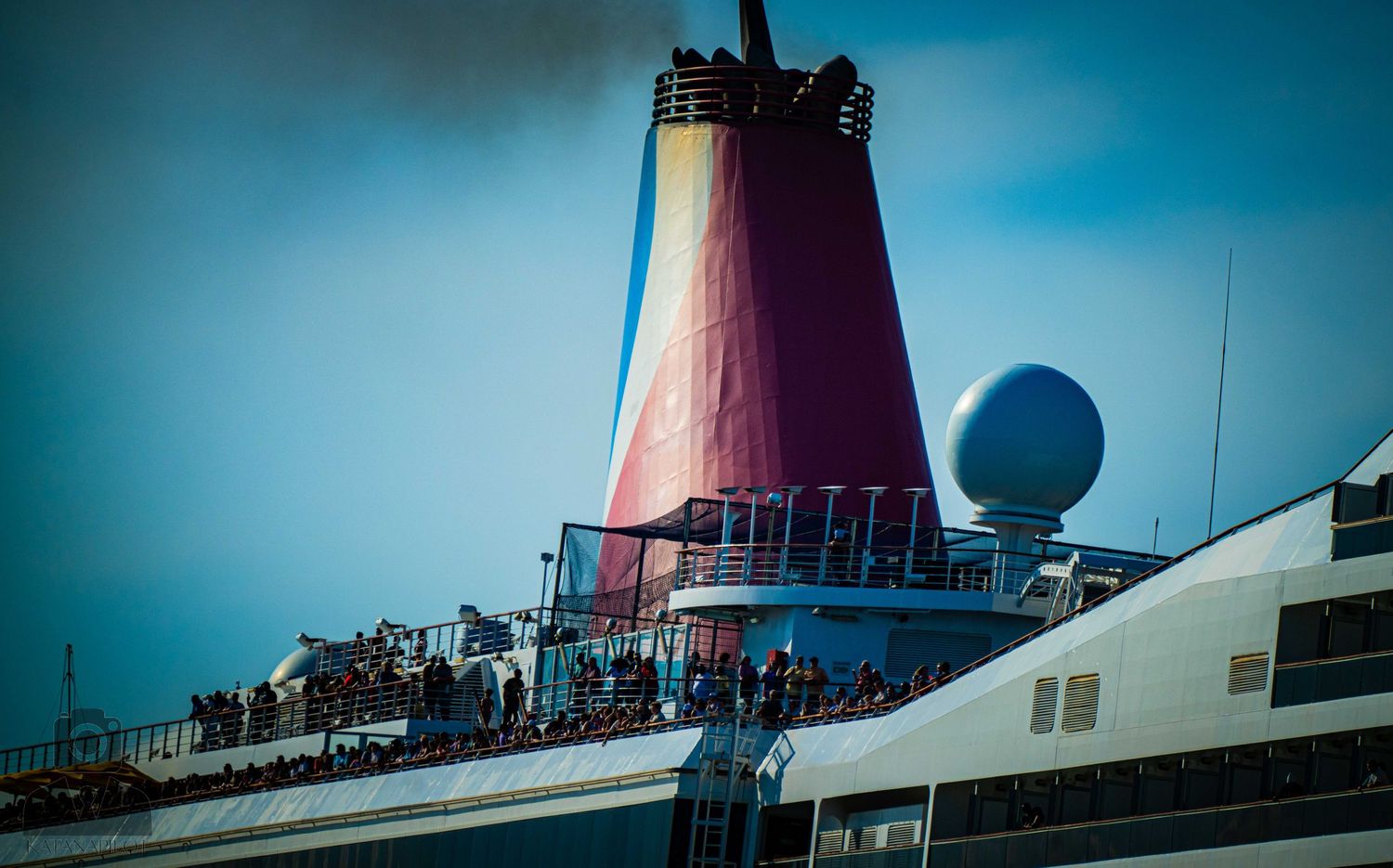 A panoramic sequence of a cruise ship's deck and smokestack against a bright blue sky.