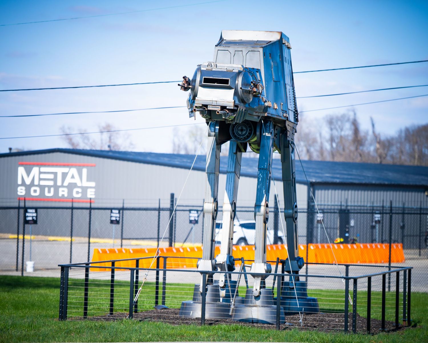 Large Star Wars AT-AT Walker replica display outside a metal building.