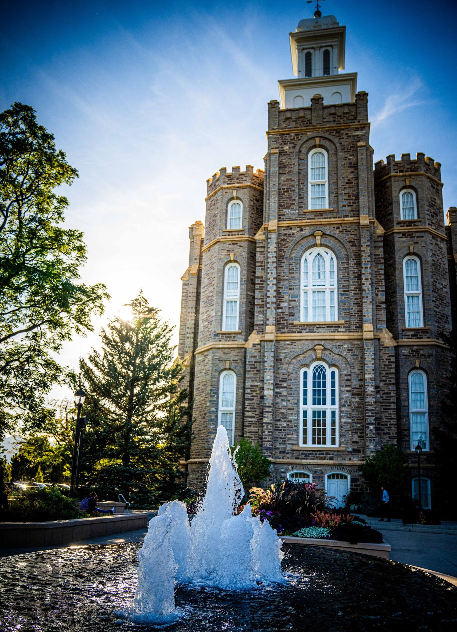 Stone church building with Gothic architecture features a flowing water fountain in the foreground.