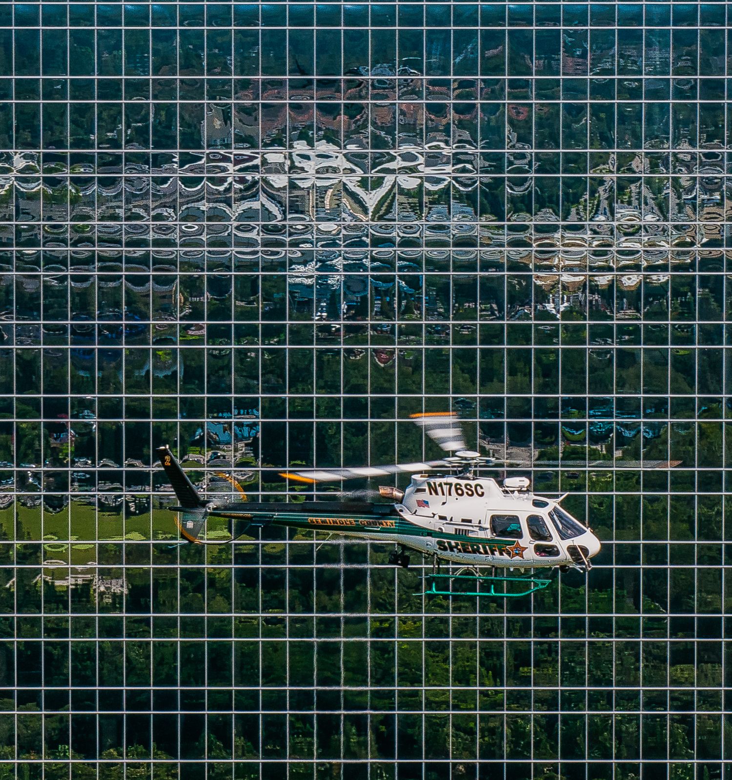 Multiple helicopters parked behind safety fence at modern heliport facility.
