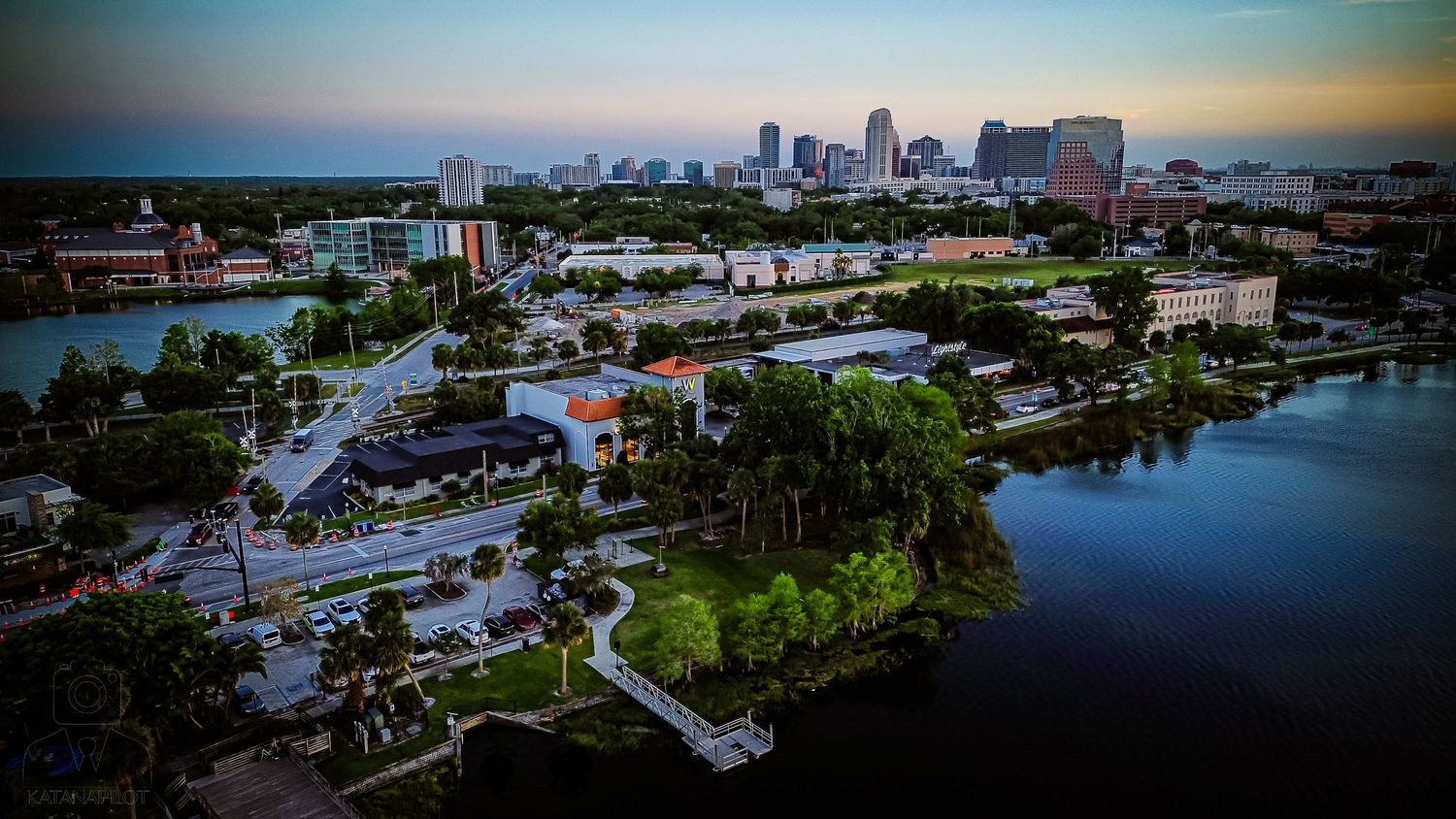Panoramic aerial view of a waterfront city skyline during golden hour.