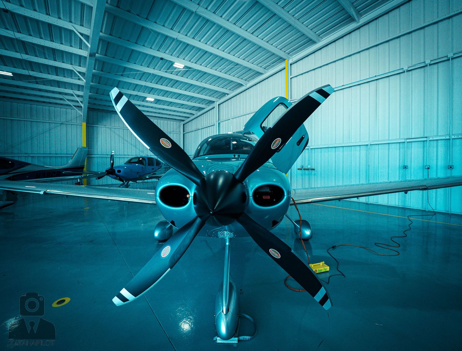 Military drones displayed in an industrial hangar under cool blue lighting.