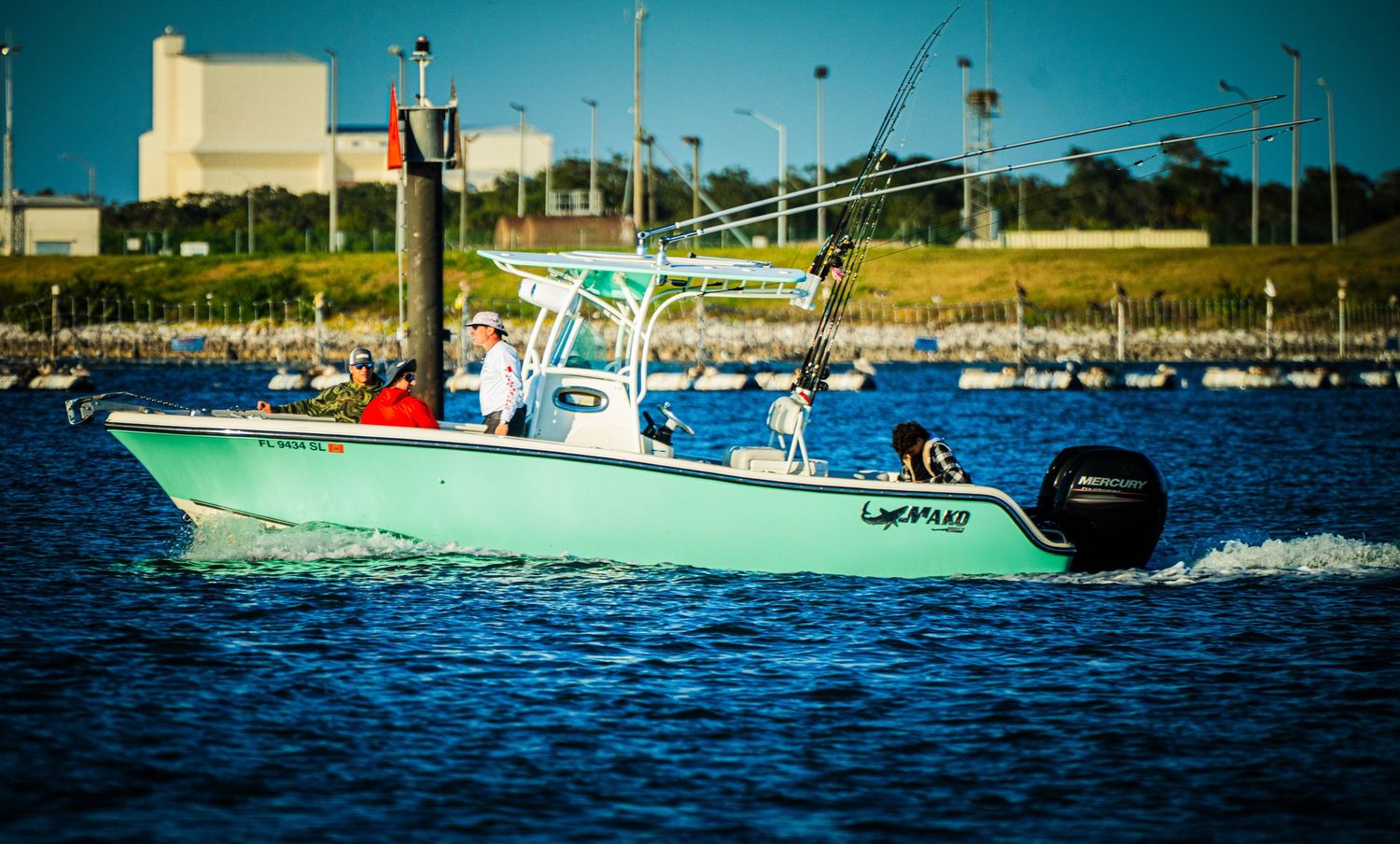 A series of boats cruising across bright blue waters on a sunny day near a coastal shoreline.