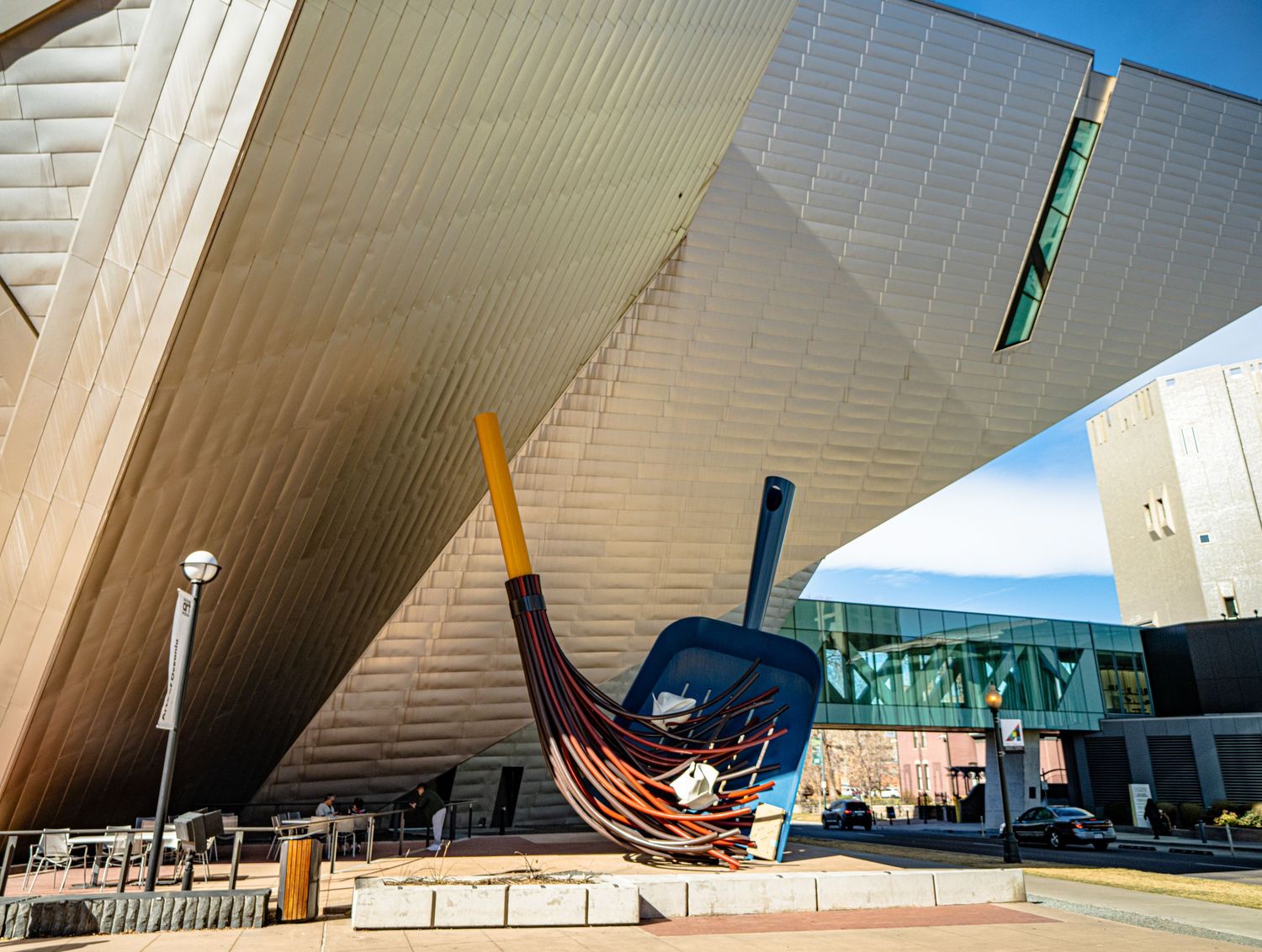 Modern angular architecture of the Denver Art Museum with a large boat sculpture displayed under an overhanging structure.