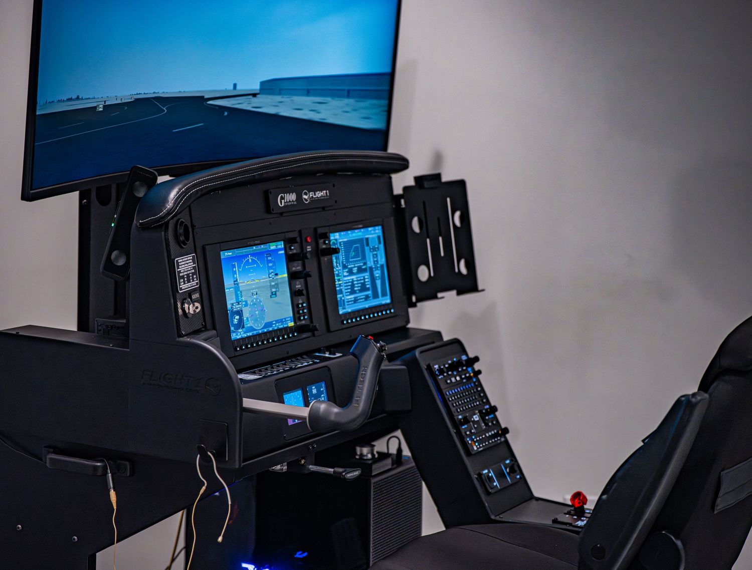 Aviation training simulator with multiple digital displays in dark room.
