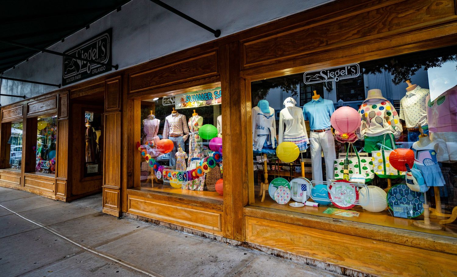 Retail display windows showcasing colorful merchandise in wooden storefront frames.