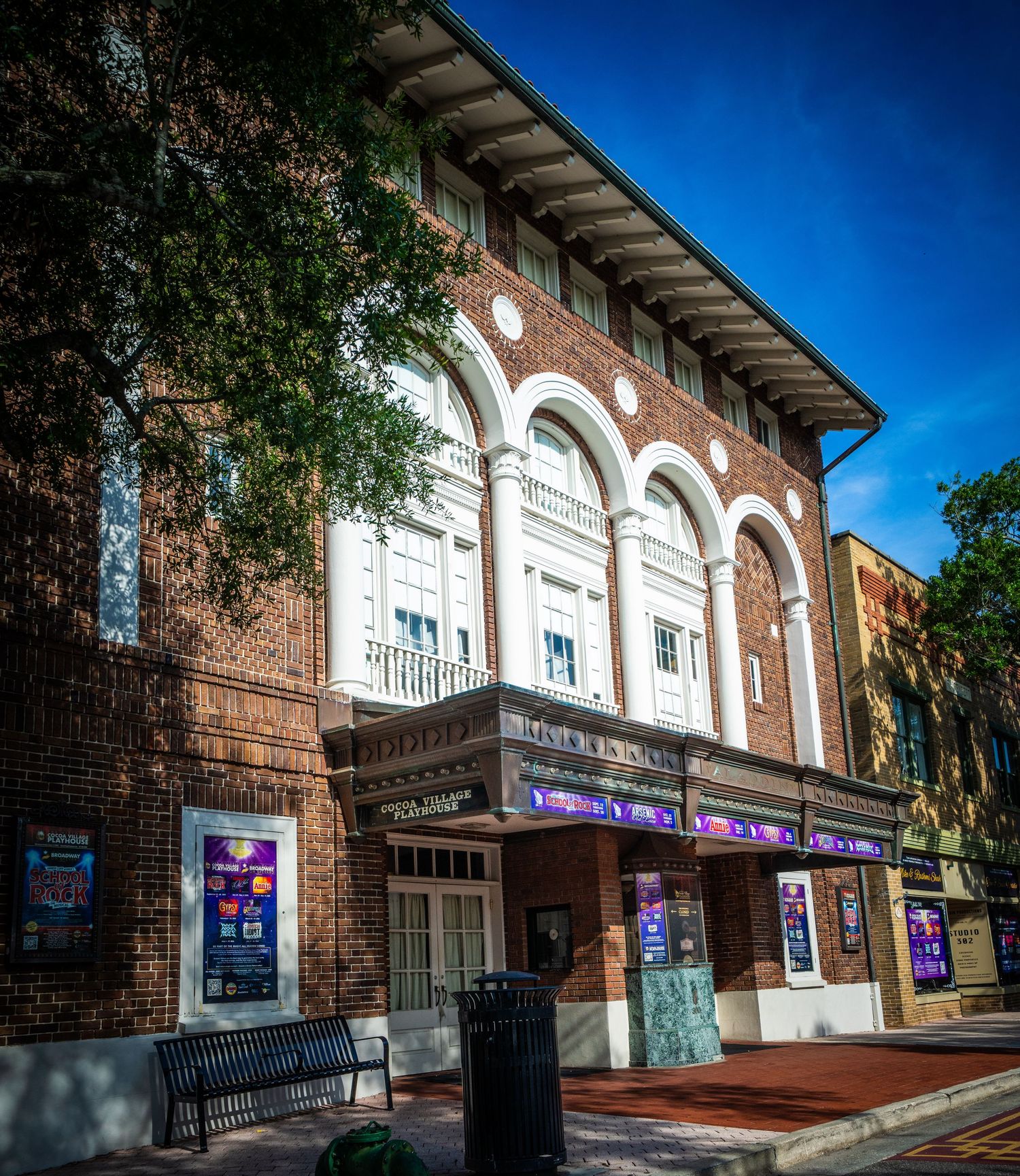 Historic brick theater building with white arched windows and ornate architectural details.