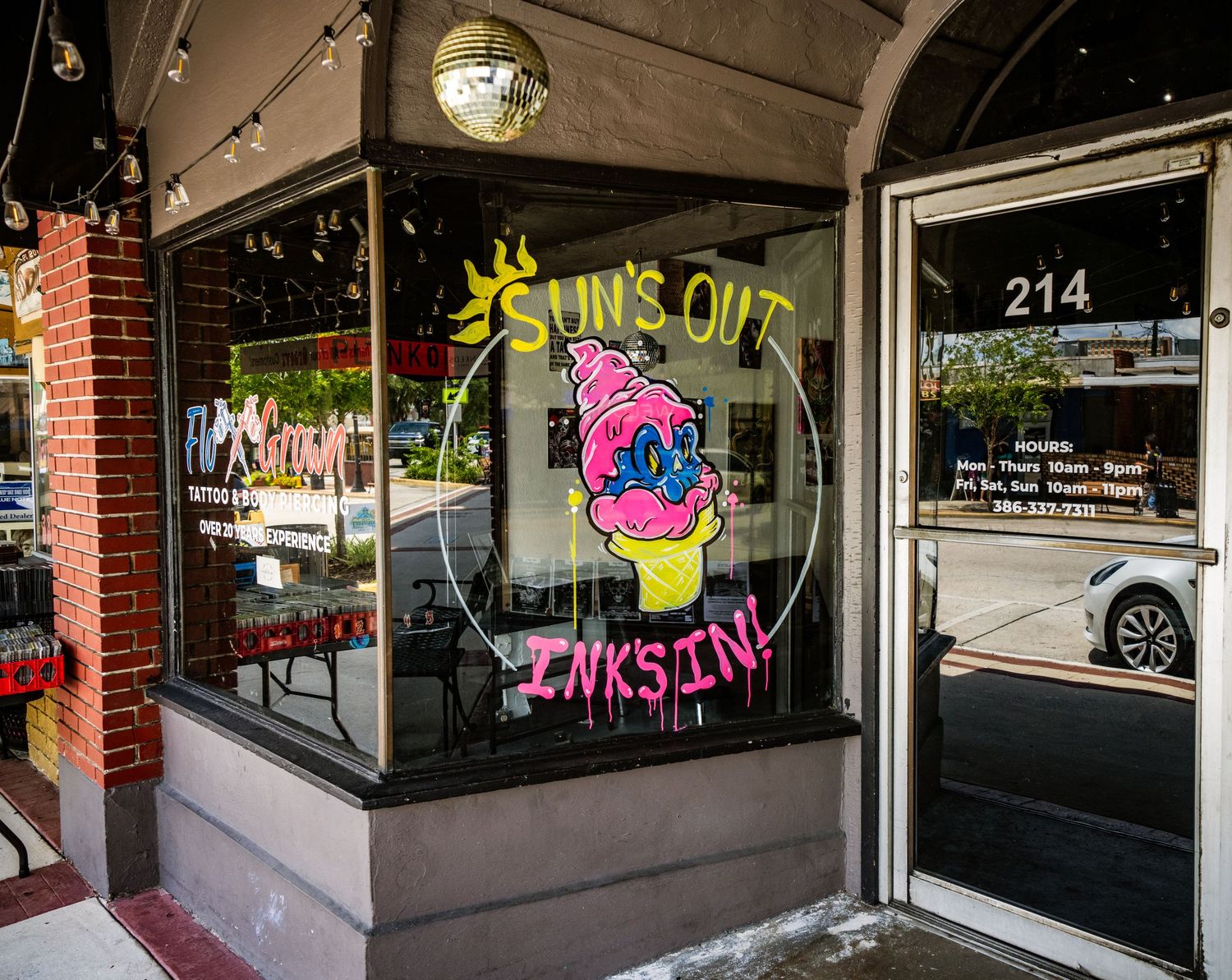 Street-level view of storefront windows with neon signage in a downtown district.