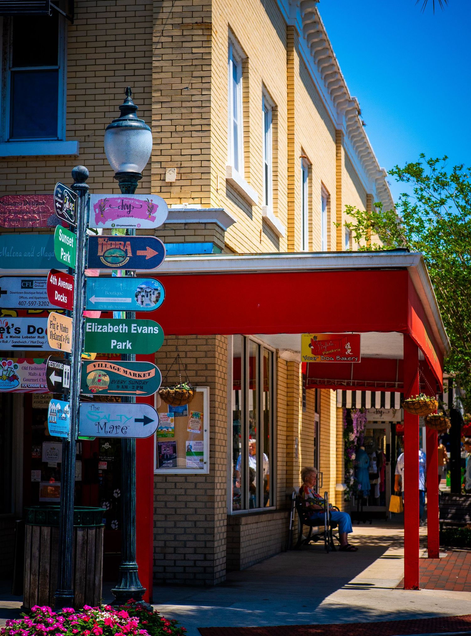 Historic brick building with red awning and decorative lamp post featuring multiple directional signs.