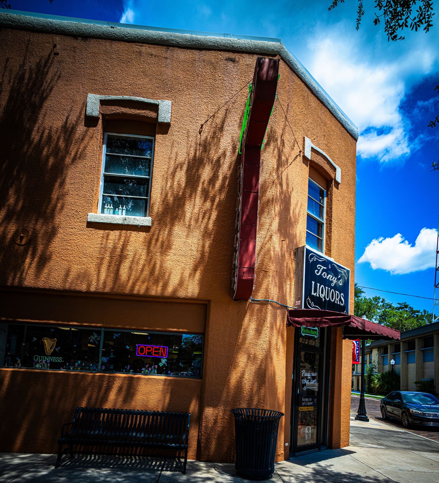 Brick commercial building exterior with windows and signage under bright blue sky and dramatic shadows.