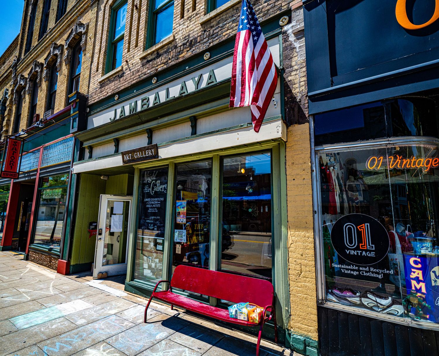 American flag hangs from historic brick storefront in downtown shopping district.