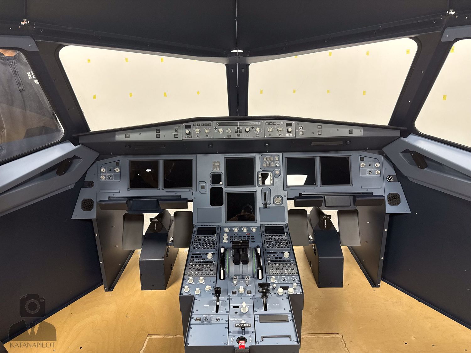 Panoramic view of a modern aircraft flight deck simulator with detailed instrument panels.