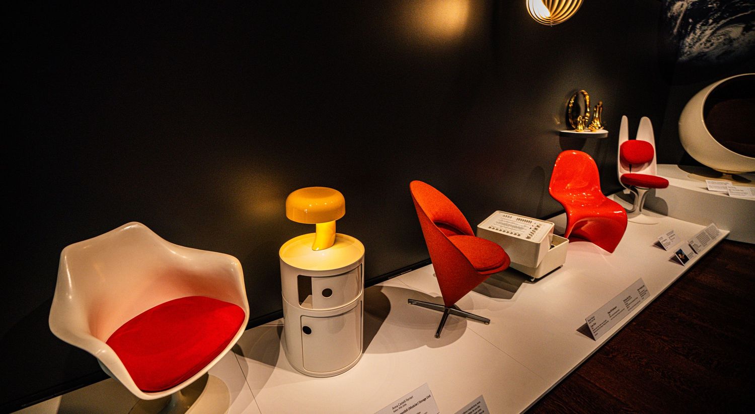 A series of six abstract white sculptural forms with red accents displayed in a gallery-like setting under dramatic lighting.