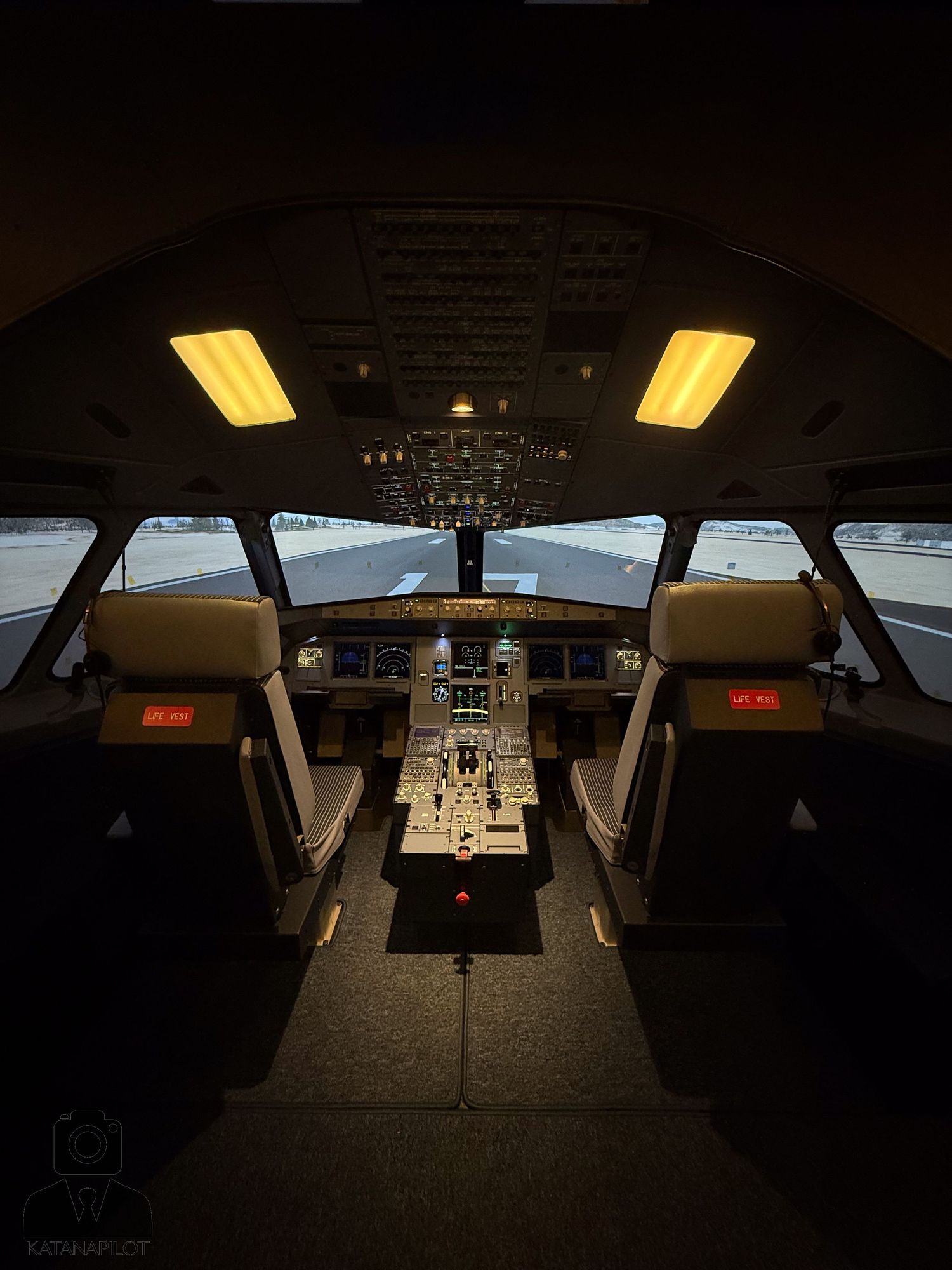 Aircraft cockpit control panel and instruments illuminated in darkness.
