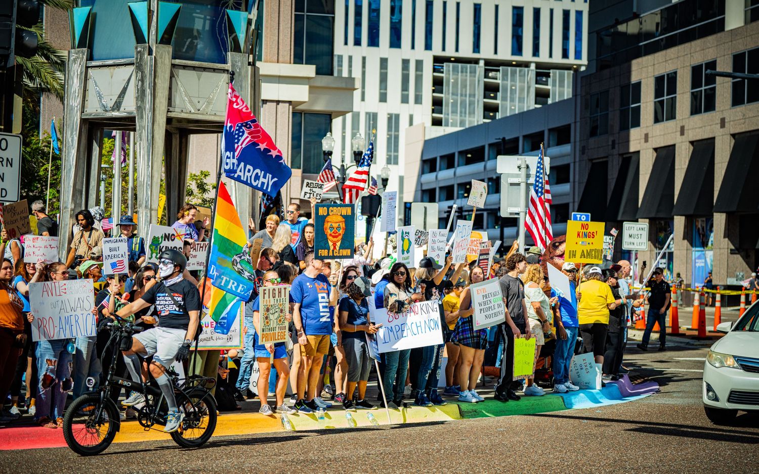 Large crowd of demonstrators line a city street with protest signs and banners.