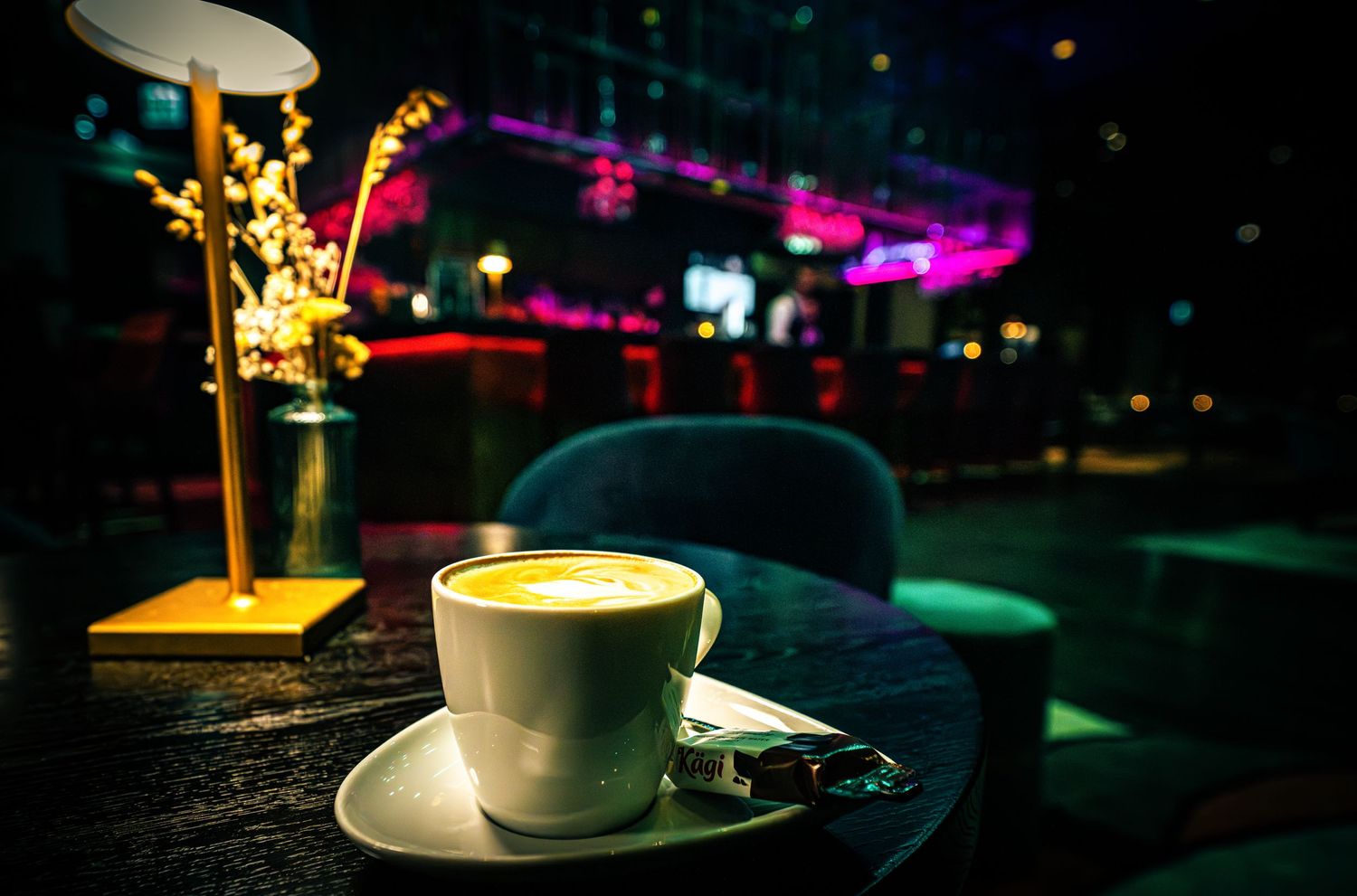 Atmospheric nightclub setting with colorful lights and coffee cup on table.