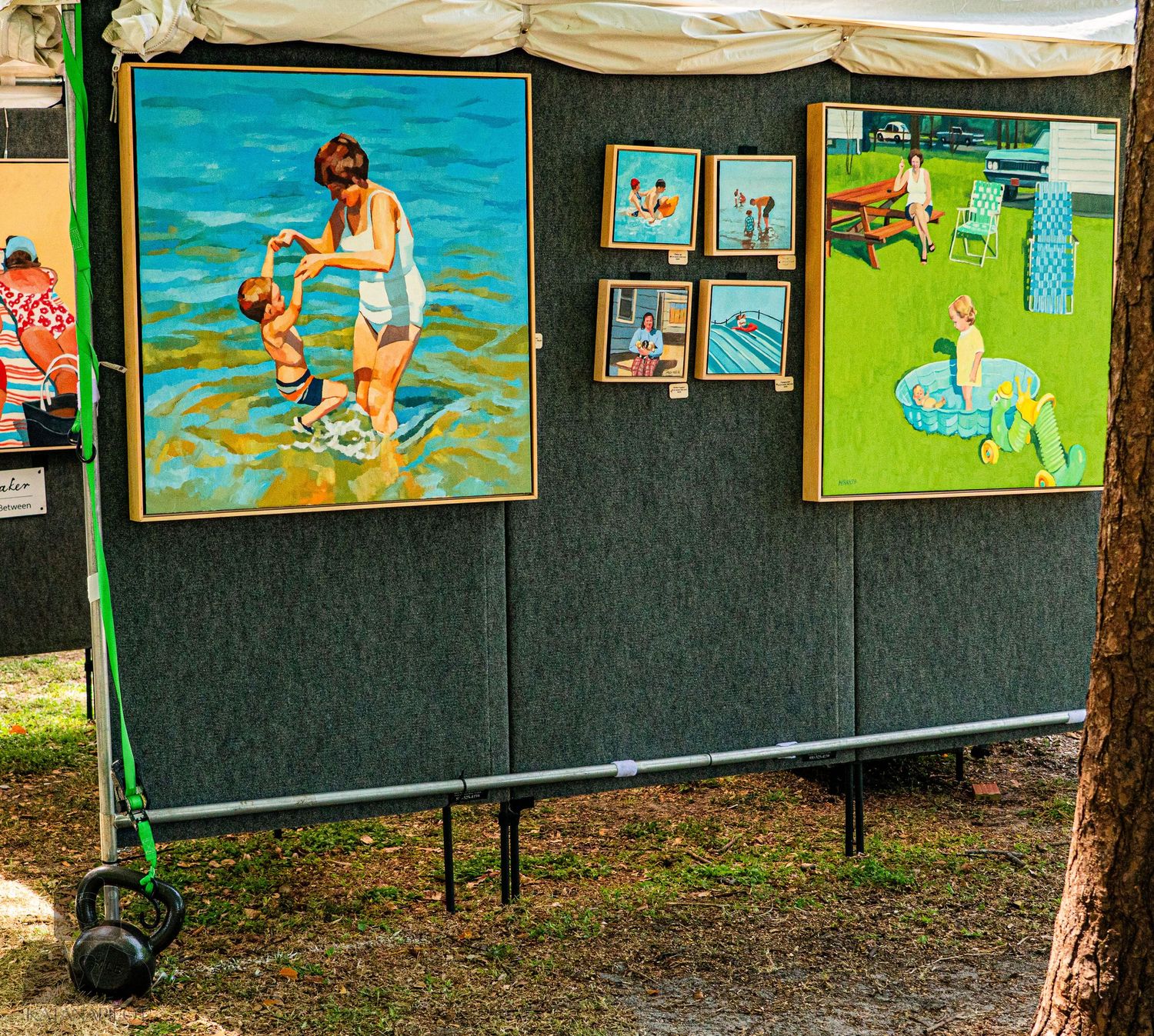 Outdoor art gallery wall displaying colorful paintings with beach and swimming themes.