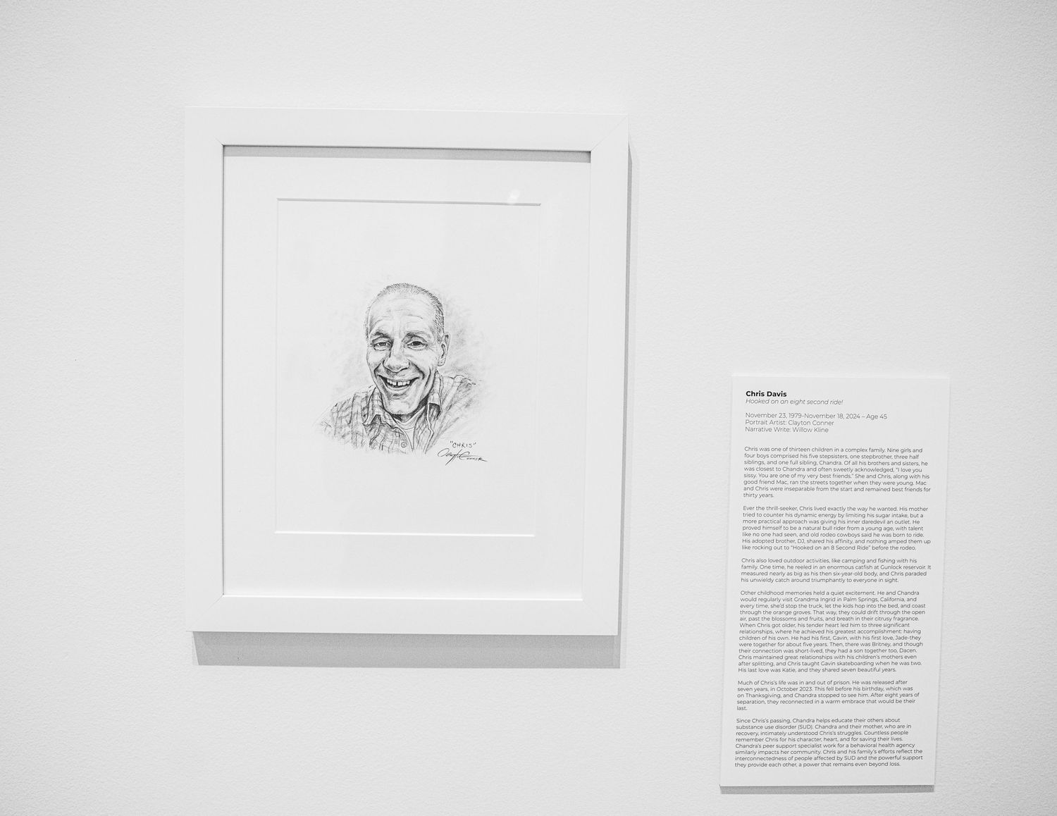 Museum display featuring portrait sketches and descriptive text panels in minimalist white space.