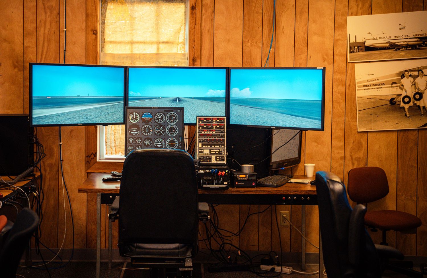 Home flight simulator room with wood paneling and multiple monitor displays.