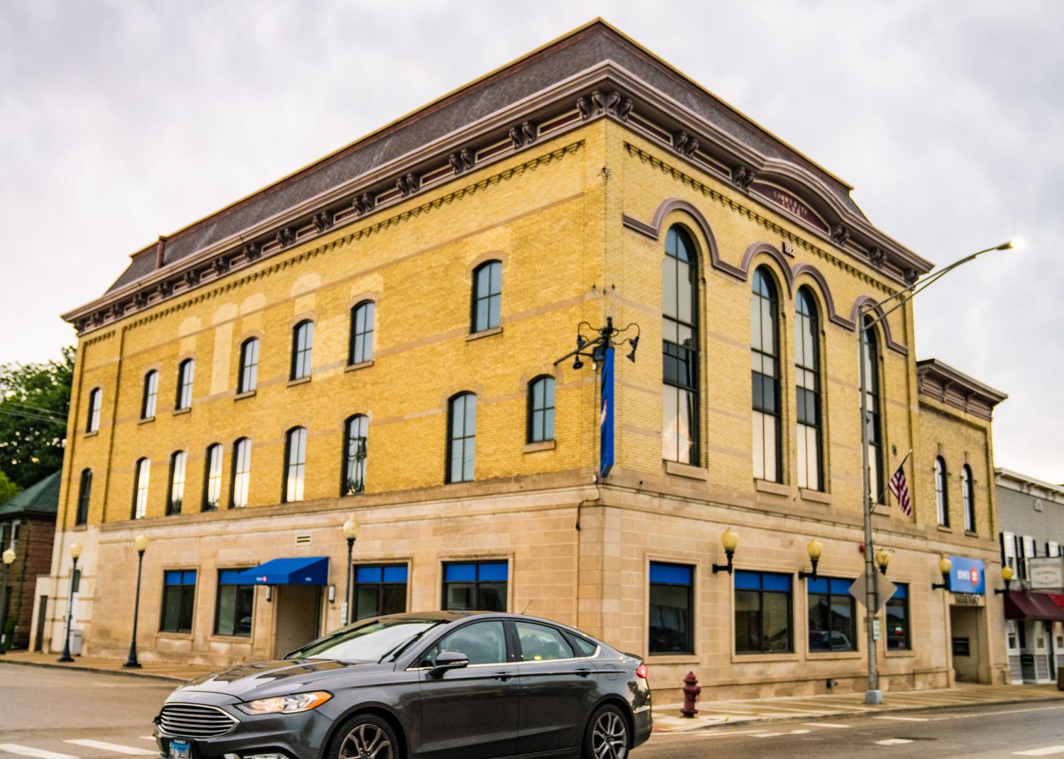 Series of connected limestone commercial buildings with classical architectural details in downtown area.