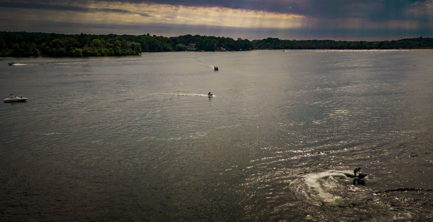Aerial view of a lake with scattered boats and forested shoreline.
