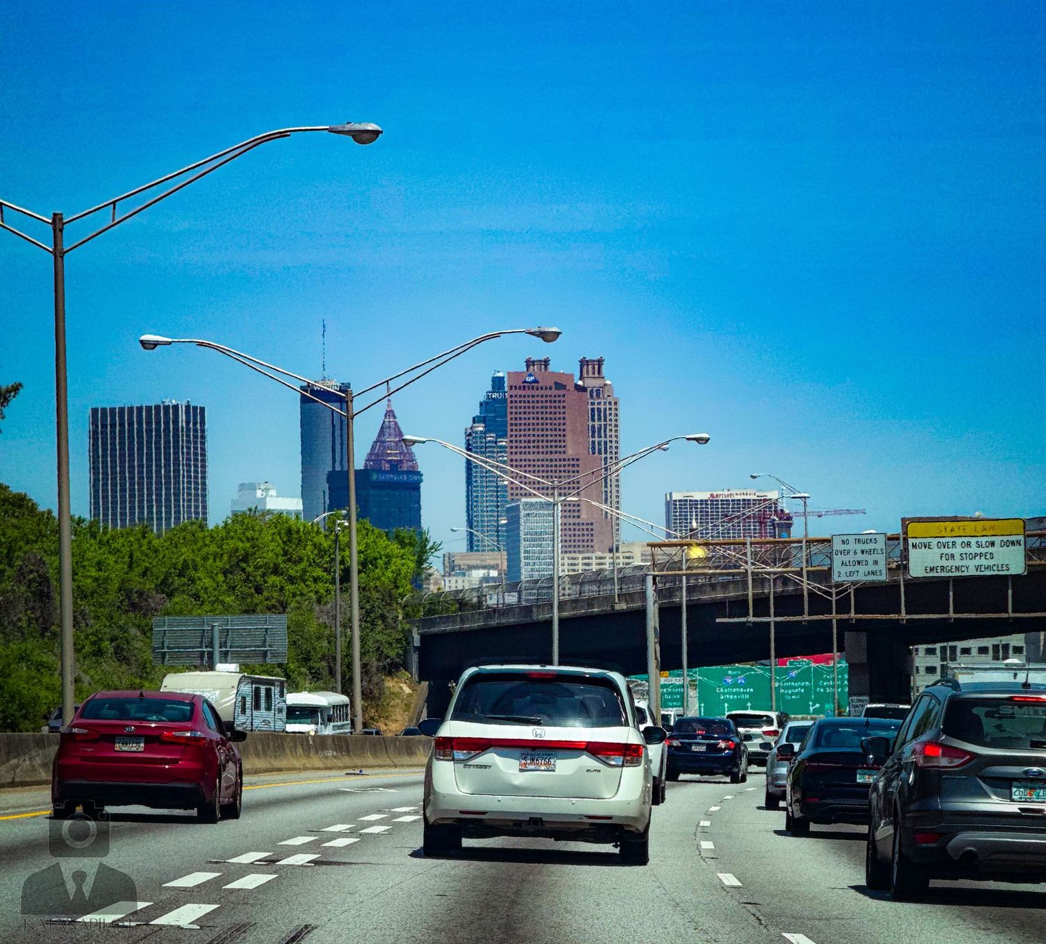 Highway driving through downtown Atlanta with modern skyscrapers and office buildings in the background.