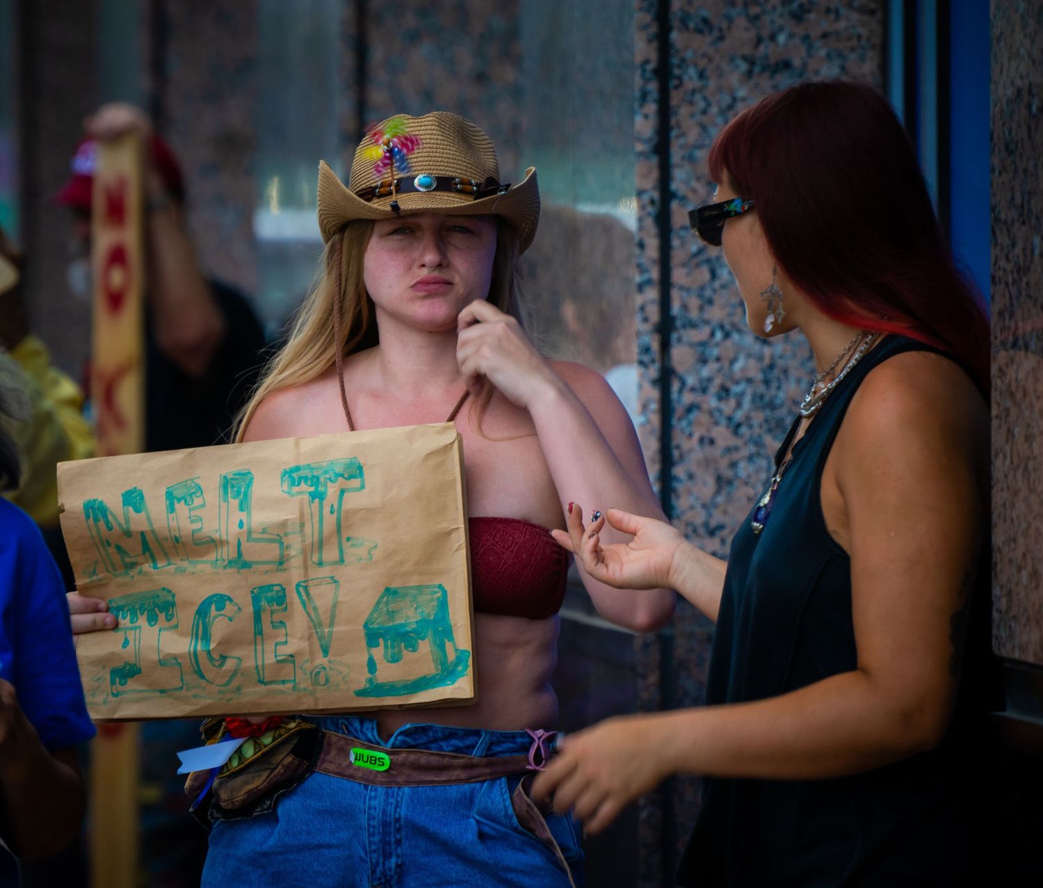 Protesters gather outside with handmade signs expressing their political views and messages.