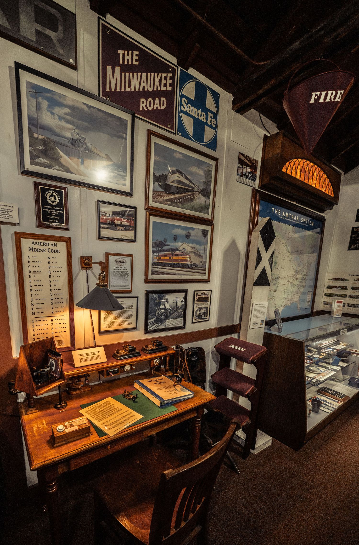 Railroad museum interior with vintage photographs and memorabilia displayed along wall-mounted cases.