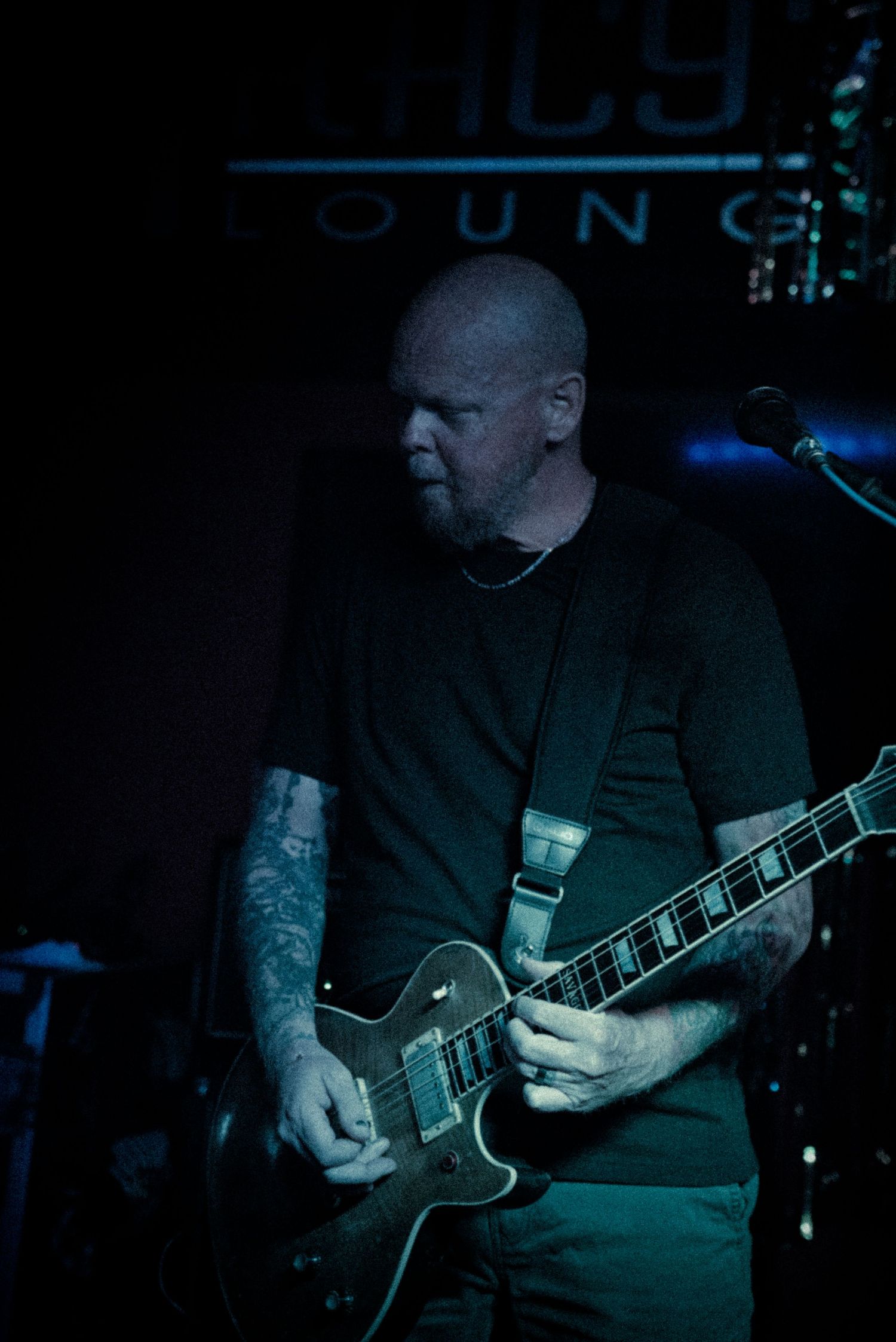 Close-up shots of a guitarist playing an electric guitar in a dimly lit venue with blue lighting.
