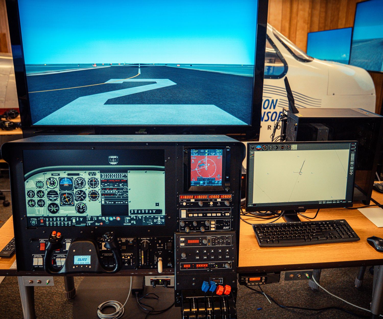 Multiple monitor flight simulator setup displaying aviation instruments and blue sky scenery.
