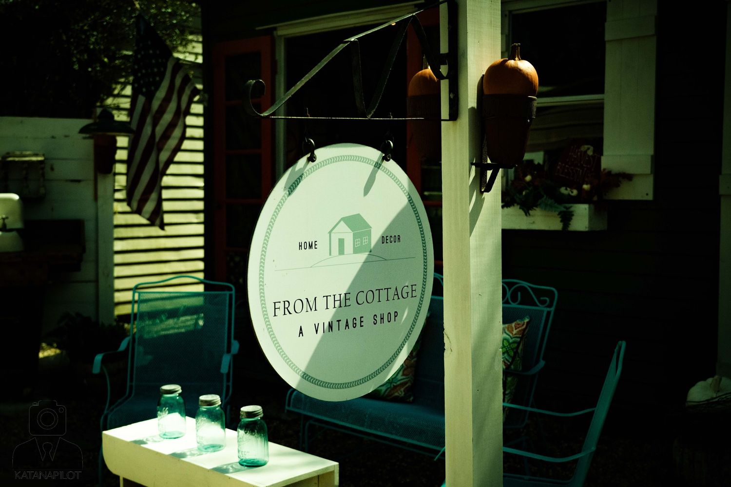 Vintage circular sign mounted on green exterior wall with atmospheric lighting.
