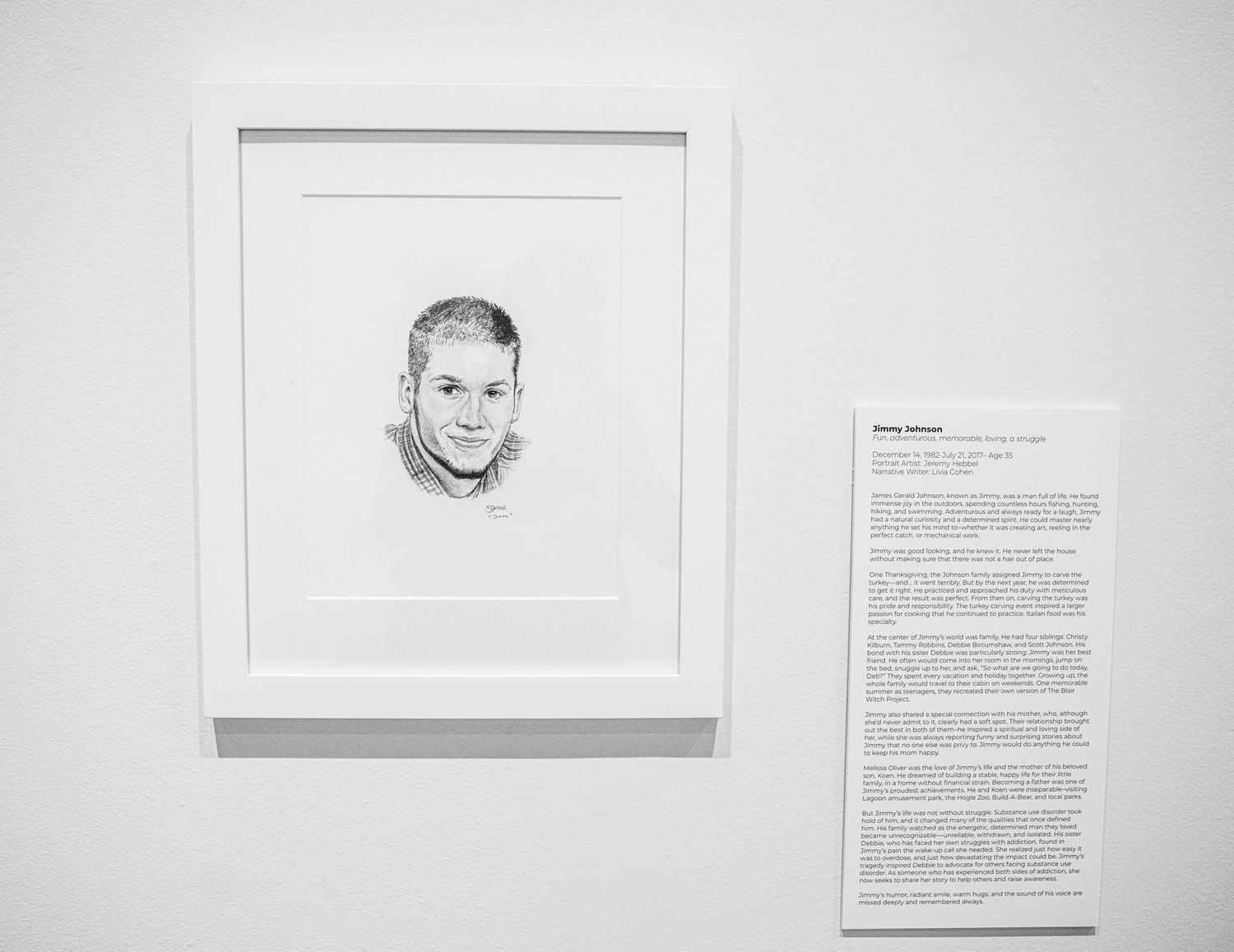 Art exhibition wall showing framed portrait sketches with accompanying written descriptions.
