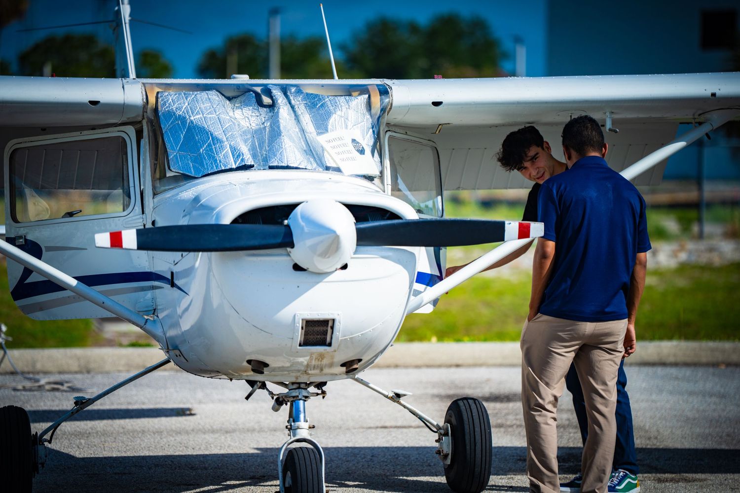 Cessna aircraft undergoing pre-flight inspection on airport ramp.