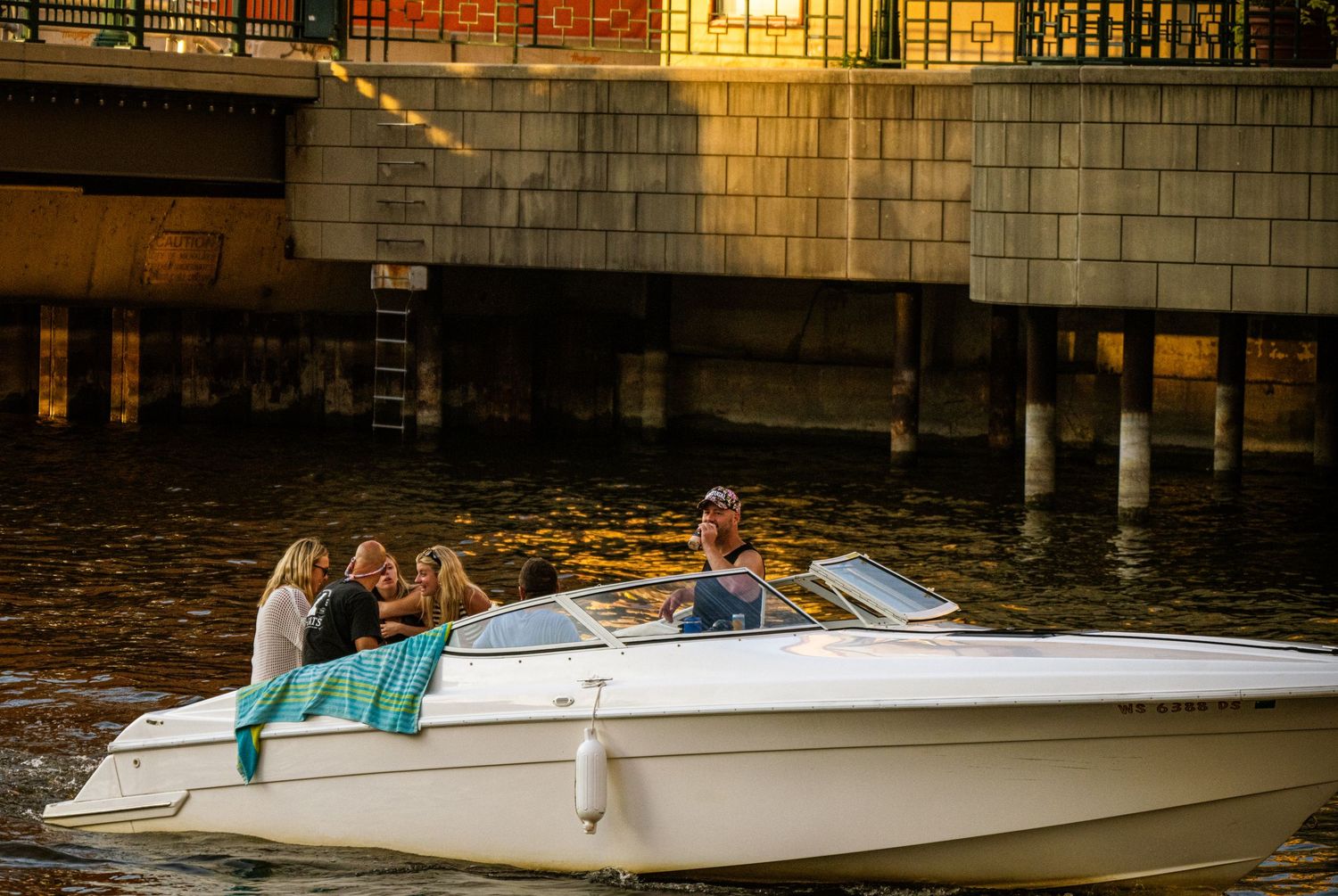 White tour boats docked along an urban waterfront with brick buildings in the background.