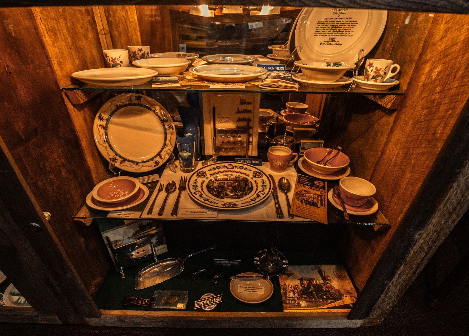 Historic railroad dining service collection featuring plates and serving pieces in wooden display cases.