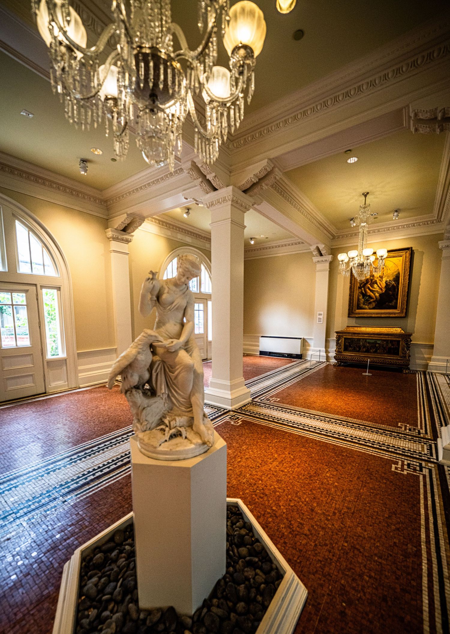 Elegant ballroom interior with crystal chandeliers, ornate columns, and patterned carpeting.