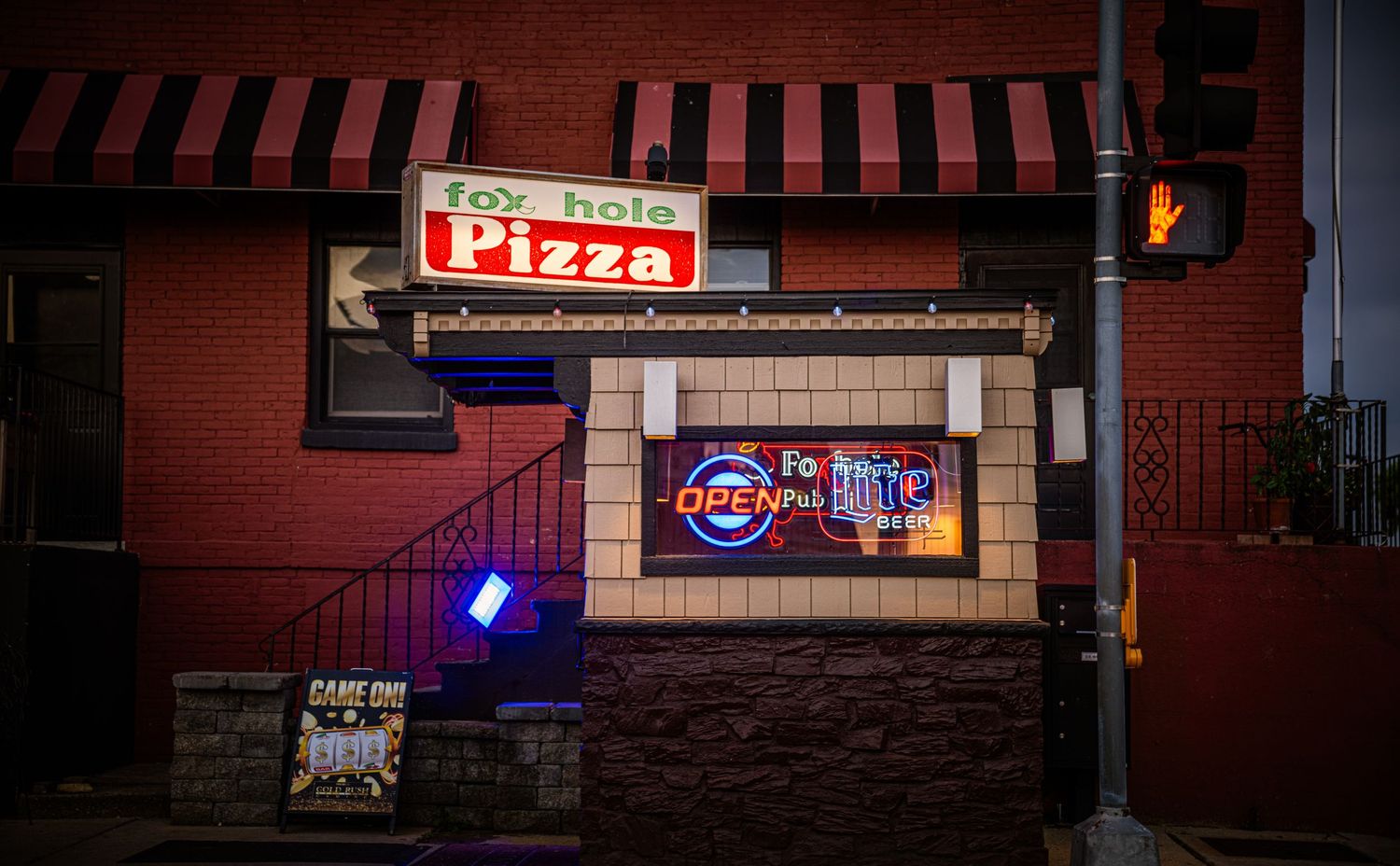 Neon signs illuminate the exterior of a dark brick building at night.