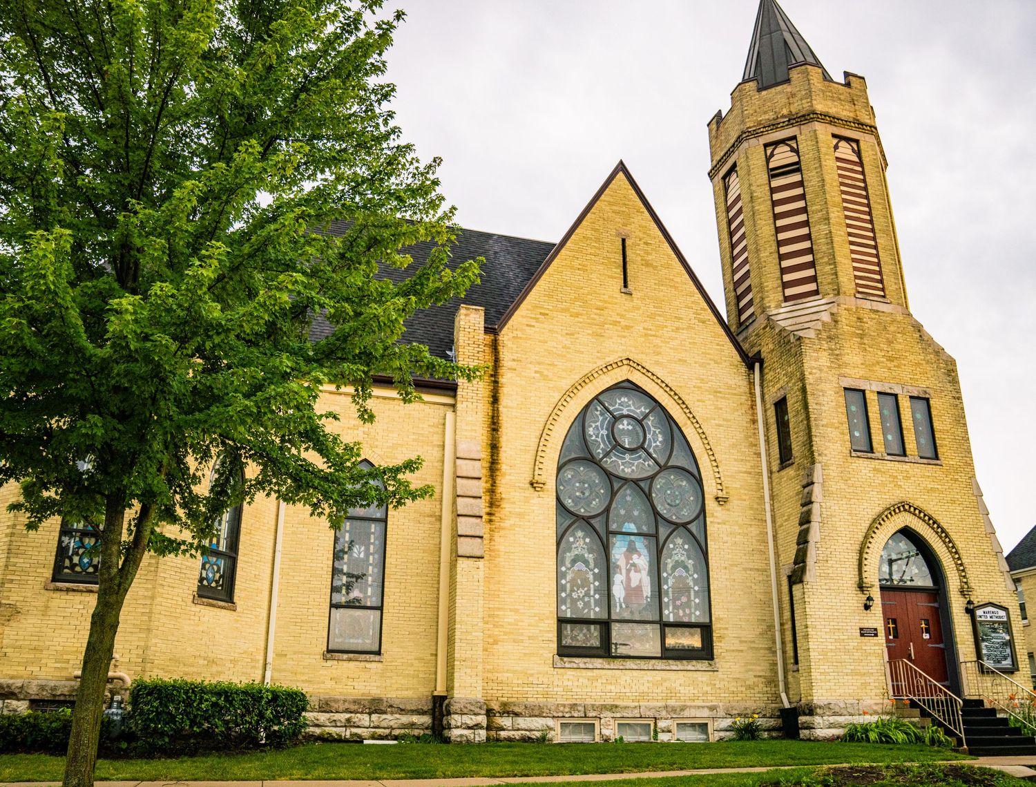 Exterior views of a traditional yellow stone church with Gothic architectural features and bell towers.