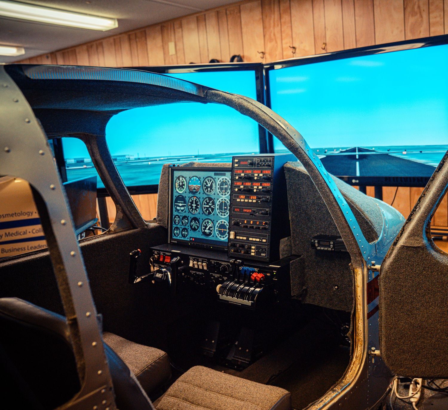 Flight simulator cockpit setup with multiple monitors and control panels showing instrument displays.