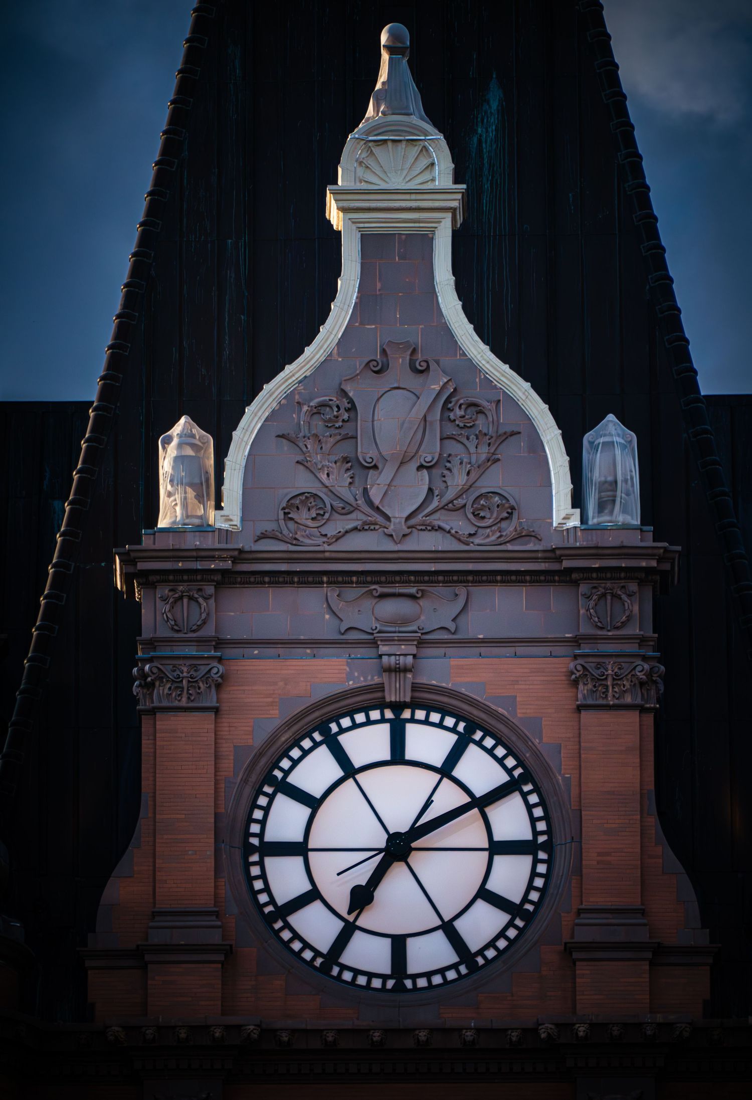 Illuminated clock tower with ornate Victorian design against dark evening sky.