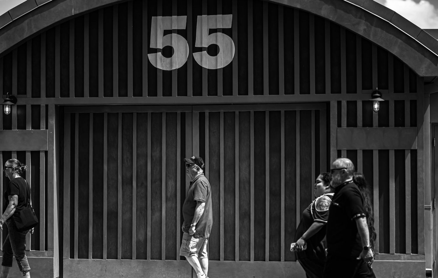 A black and white photograph shows a row of numbered storage units or garage doors in an industrial setting.