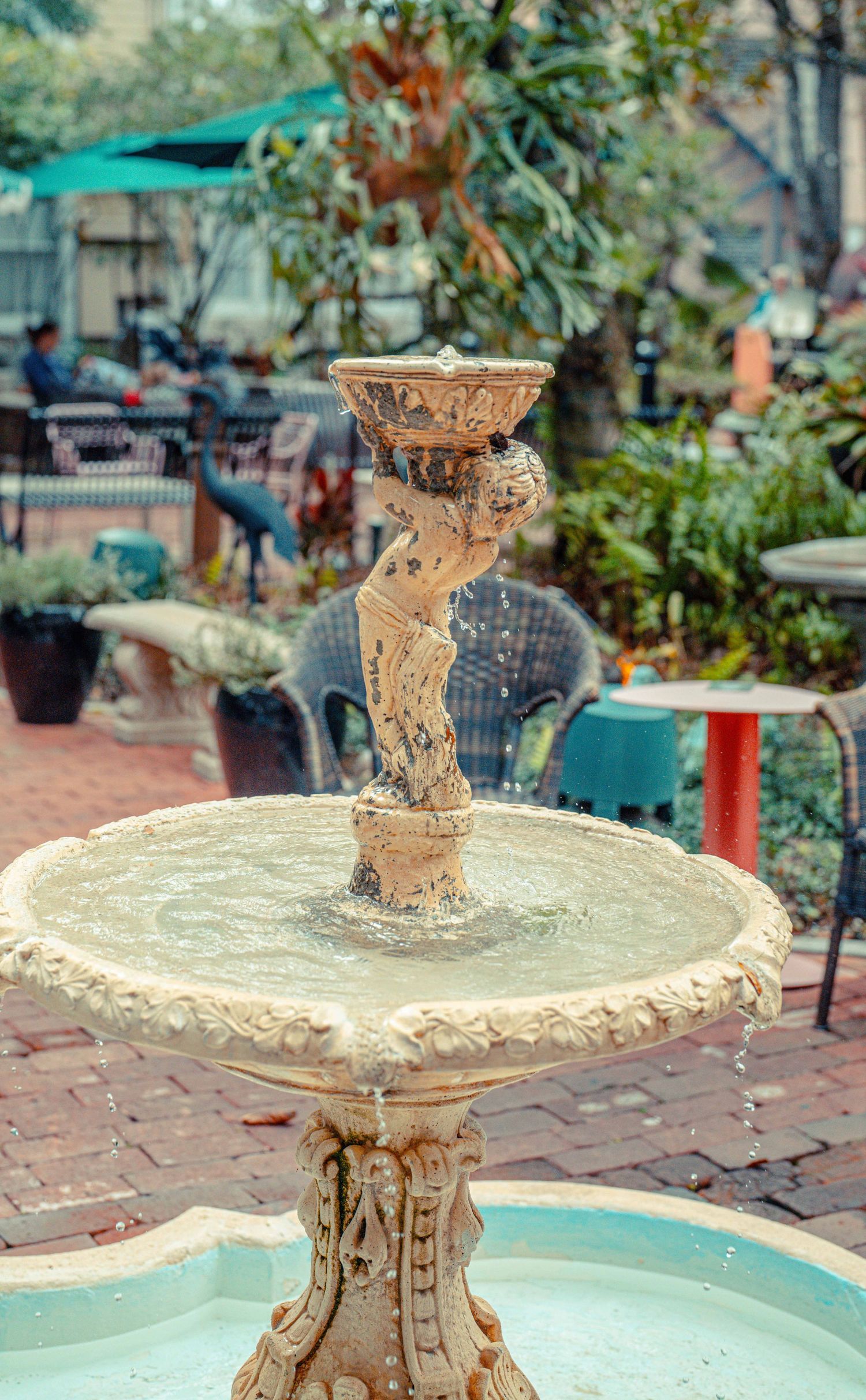 Ornate antique fountain with decorative tiered base and intricate carvings photographed in a garden setting.