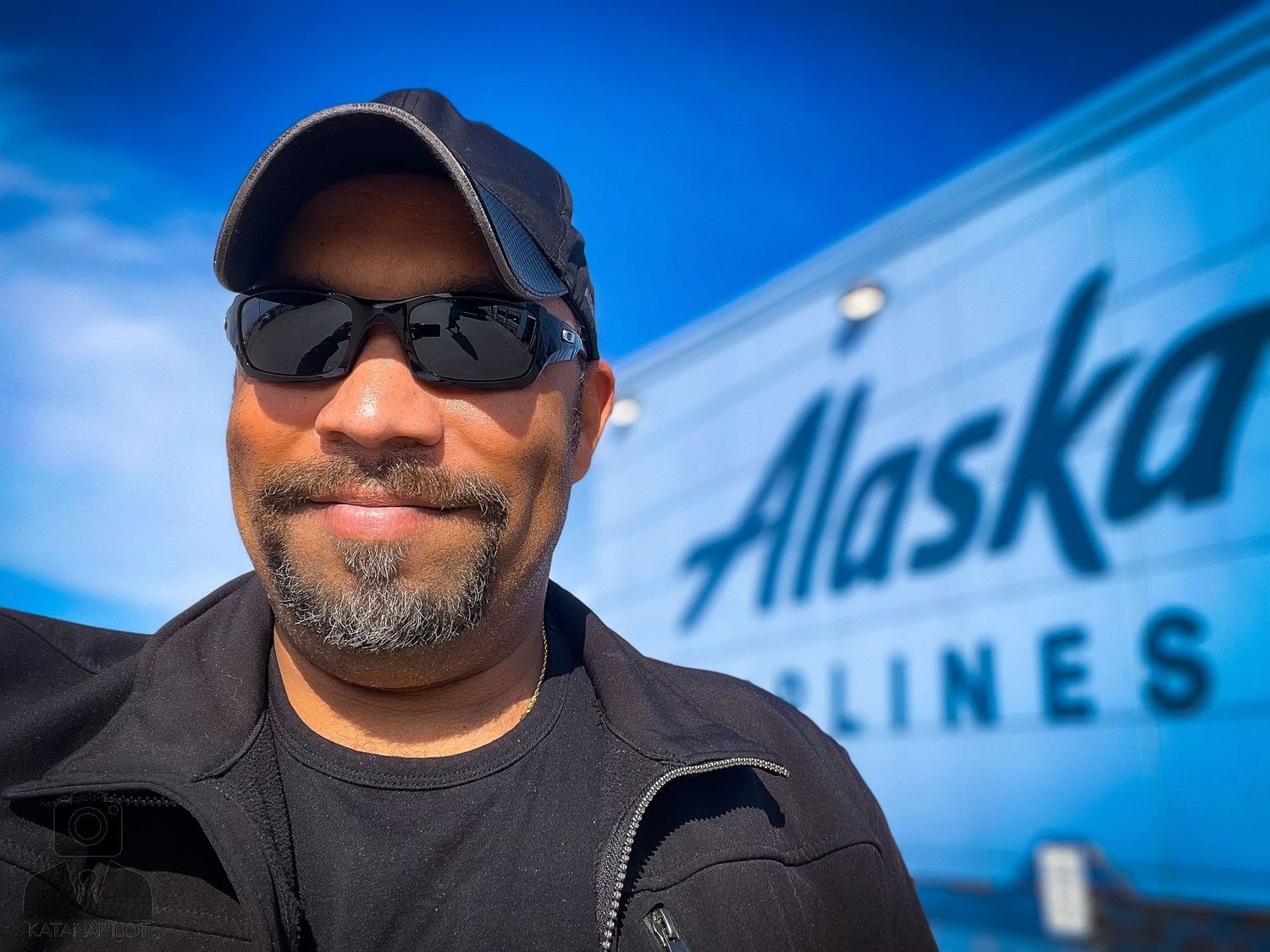 Alaska Airlines aircraft tail visible against bright blue sky.