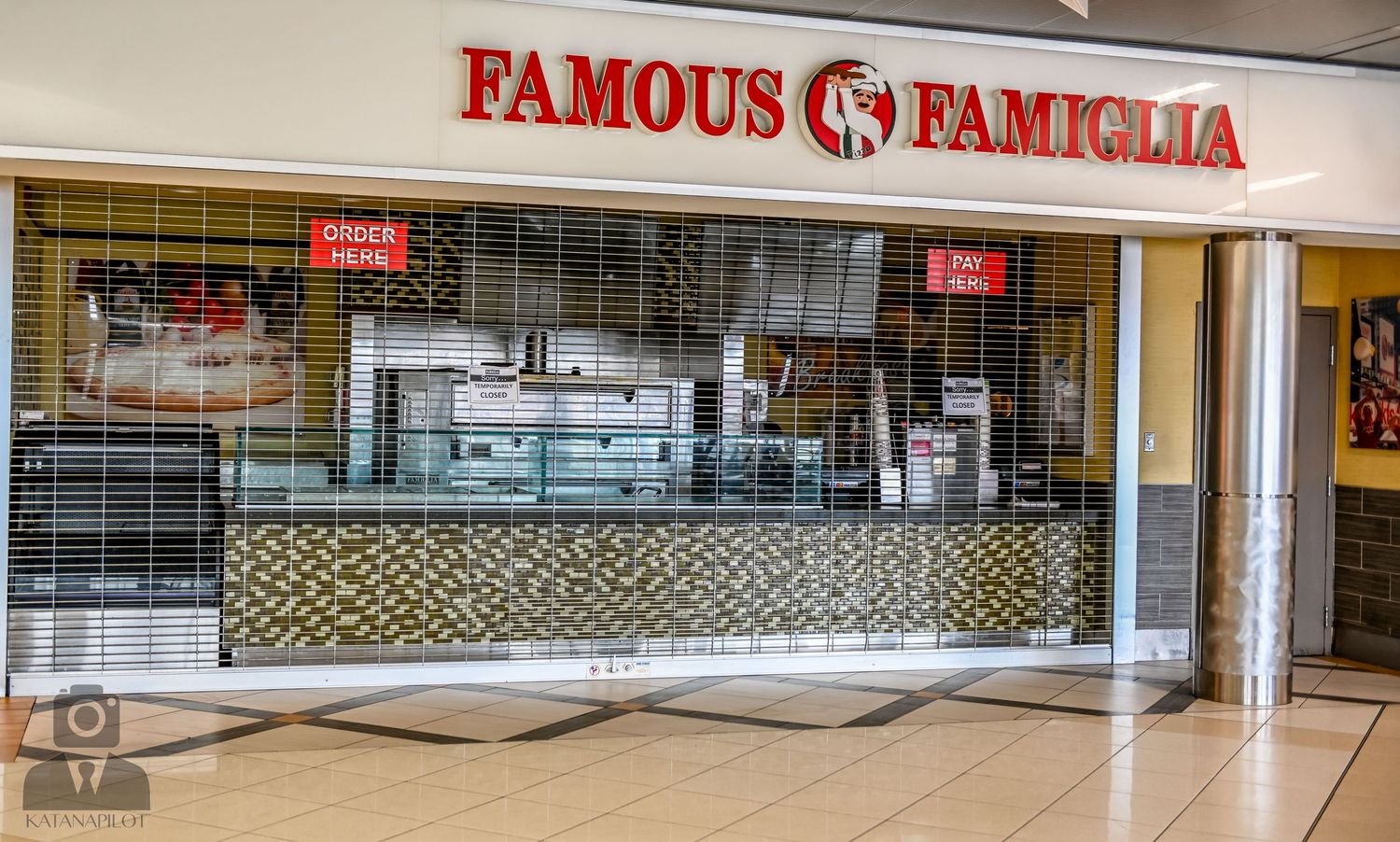 Famous Famiglia pizza restaurant storefront with security gate down in mall setting.