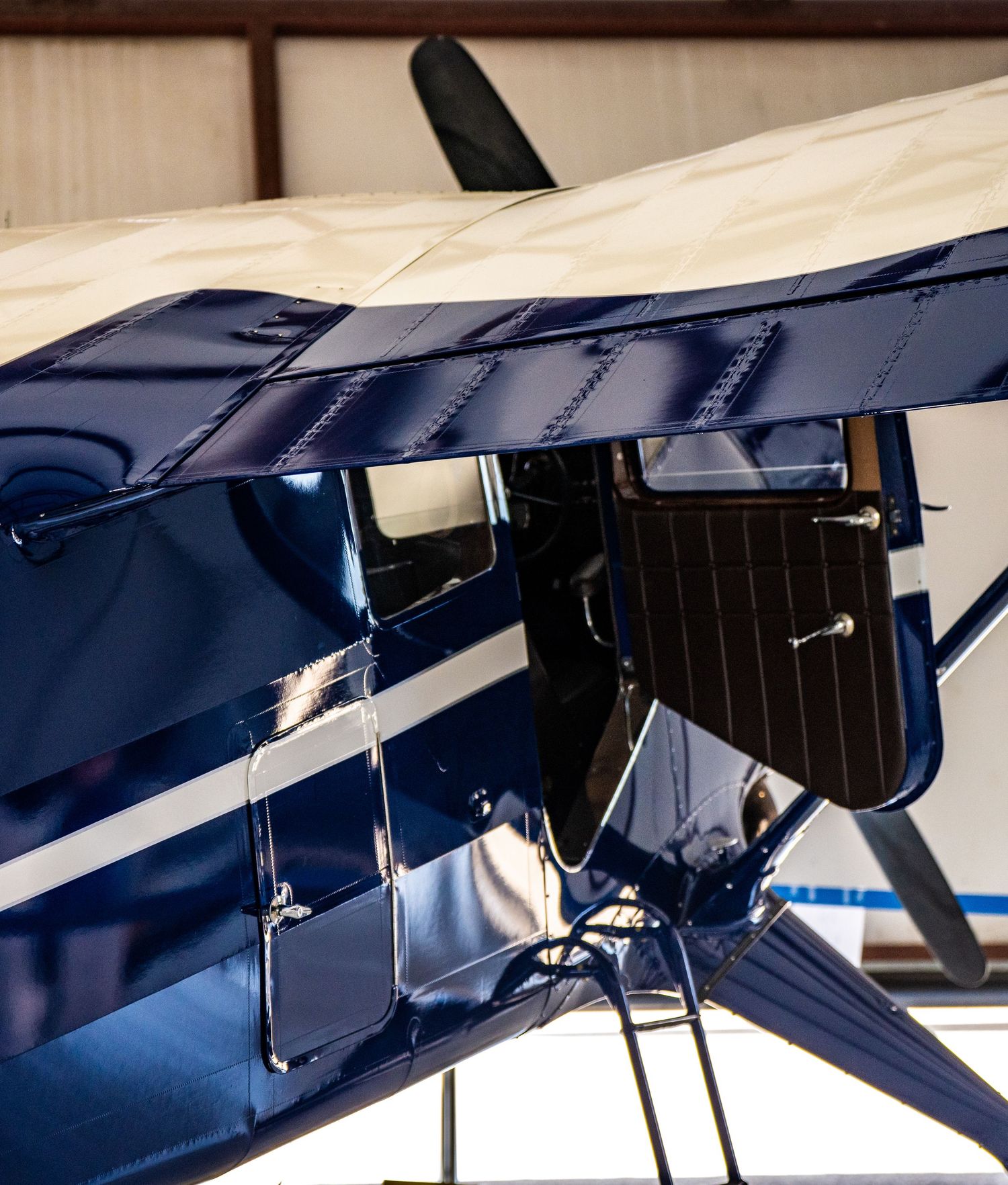Detailed shot of blue aircraft landing gear and struts against white background.