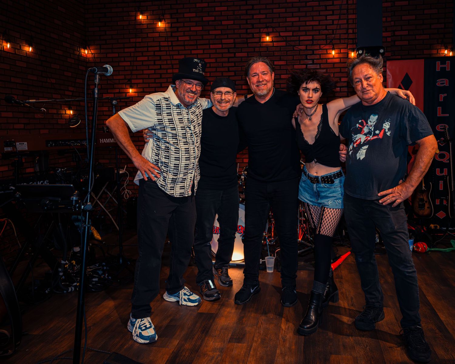 Group performance on stage at night with red brick wall and ambient lighting.
