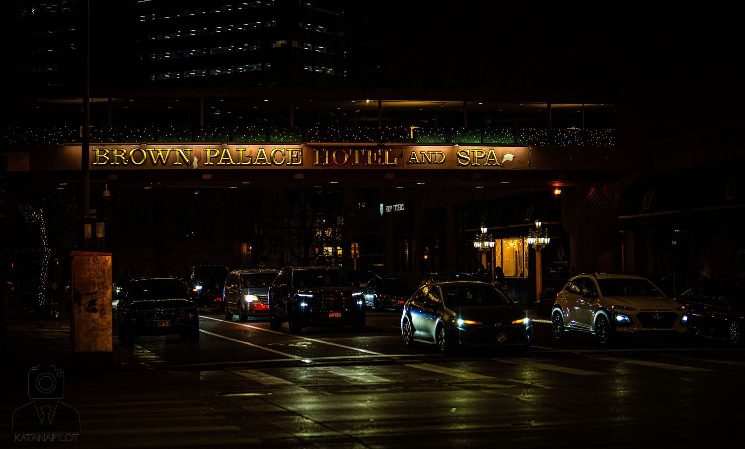 Dark nighttime street scene with illuminated hotel signage and empty parking lots visible in low light conditions.